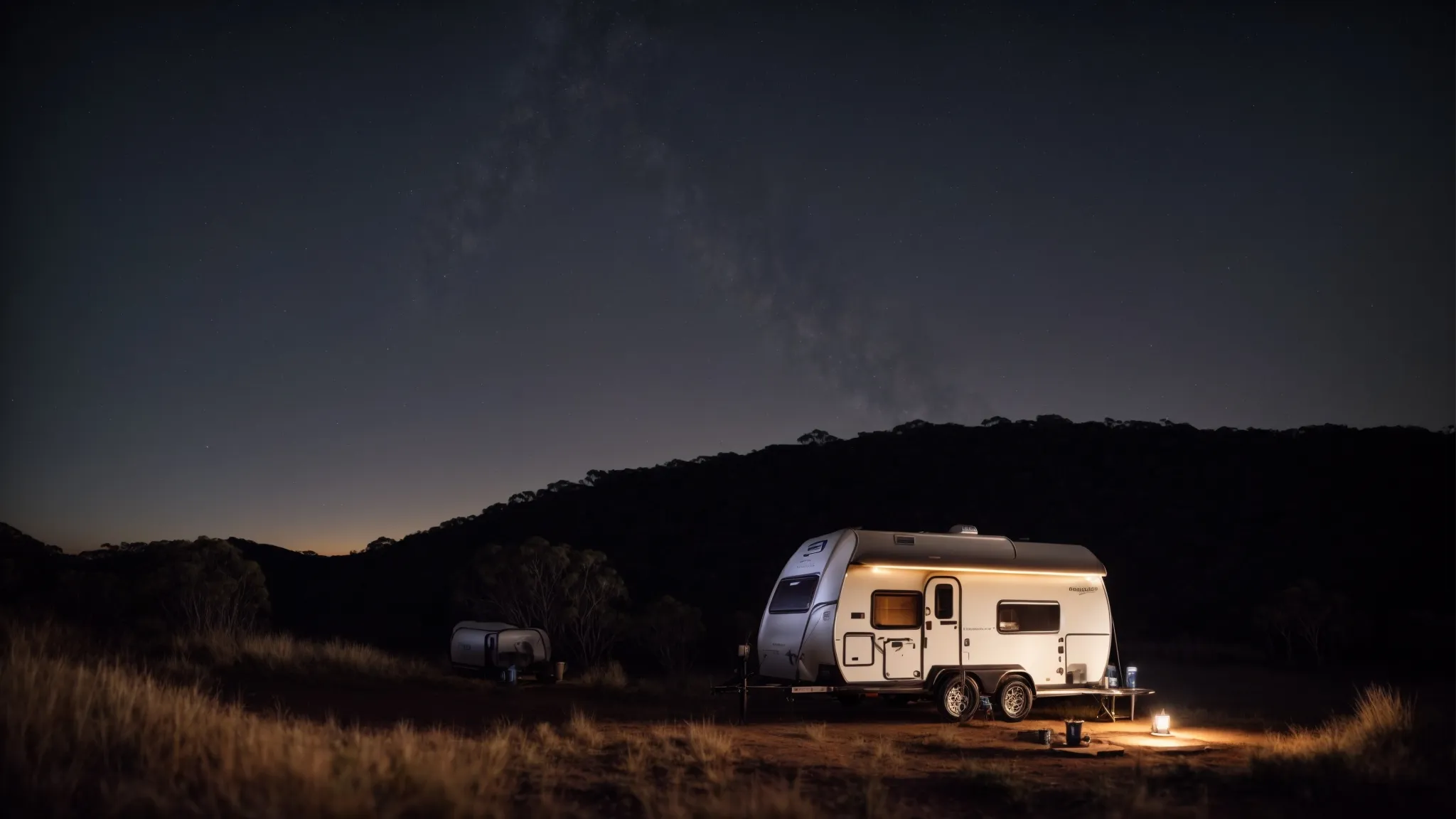 a hybrid camper trailer parked amidst the rugged australian wilderness under a starlit sky.