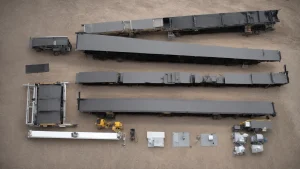 a flatbed trailer kit lies unassembled on the ground, with panels and parts spread out, ready for assembly.
