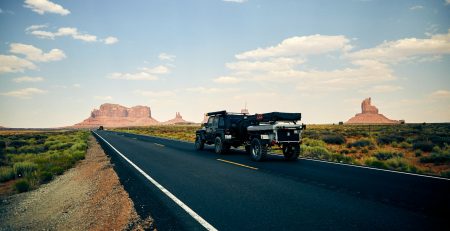 black vehicle towing trailer on black road during daytime