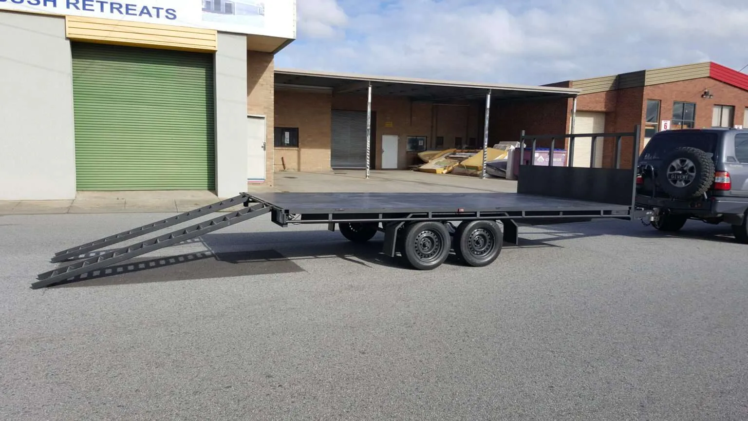 Beavertail car carrier trailer with slide-out ramps